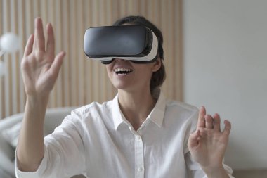 Sanal gerçeklikteki nesnelere dokunmaya çalışırken uzaktan kumandalı internet üzerinden çalışan mutlu kadın serbest çalışan. Kız masada oturuyor ve 3D görselleştirmeyle etkileşime geçiyor