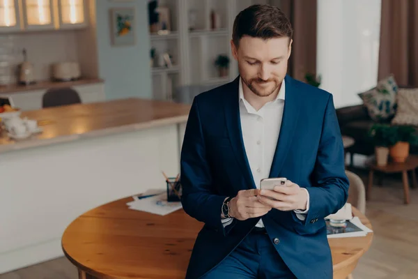 자신감 양복을 사업가가 스마트폰을 거실에서 탁자에 메시지를 읽거나 인터넷에서 마지막 — 스톡 사진