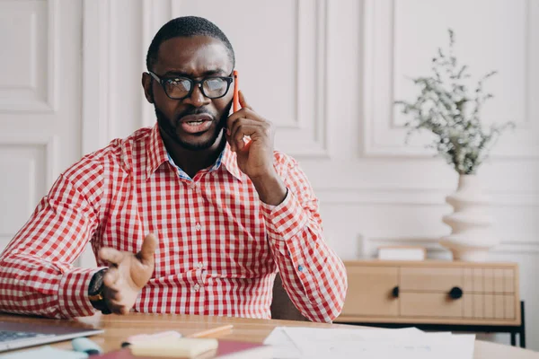 Недовольный Афроамериканский Бизнесмен Эмоционально Говорит Мобильному Телефону Сидя Рабочем Месте — стоковое фото