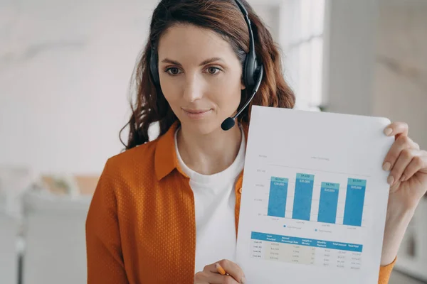 Marketing professional woman in headset talking to coworkers on video call, presenting graph reports, showing, explaining chart. Female employee, manager business coach speaking at online meeting.