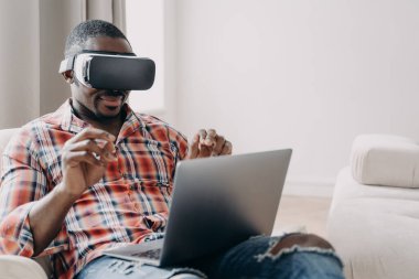 Sanal gerçeklik gözlüğü takan Afro-Amerikalı yazılım geliştirici sanal dünyada çalışıyor, dizüstü bilgisayarda uygulama yaratıyor. Modern siyahi adam programcısı VR gözlüklü serbest yazar oyun uygulaması yaratıyor.