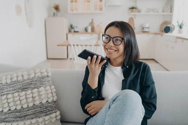 Mujer Sonriente Con Gafas Sostiene Teléfono Inteligente Charlando Sentado Sofá —  Fotos de Stock