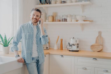 Yakışıklı, sakallı, gündelik kıyafetler giyen, evden uzakta internet üzerinden çalışırken cep telefonuyla konuşan, sözleşmeyi imzalama konusunda müşteriyle başarılı bir konuşma yapan bir adam.