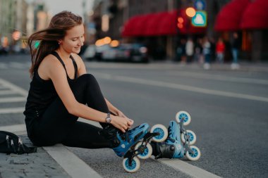 Açık hava aktiviteleri yaşam tarzına uygundur. Aktif bir kadının yan görüntüsü yol ayarları patenler patenler paten hazırlıkları iç paten takmalar rüzgarda süzülen saçlar hafta sonu en sevdiği hobi.