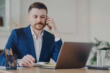 Ciddi bir iş adamı masaüstü pozisyonunda dizüstü bilgisayarla yapılan telefon görüşmelerini yoğunlaştırıyor. Günlük planlarına, resmi giysiler içinde yoğun çalışma saatlerine notlar yazıyor. Dijital yönetim