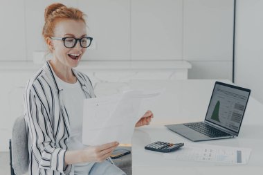 Genç kızıl saçlı kadın banka tebligatı ya da son ipotek ödemesiyle ilgili haberleri okurken çok mutlu hissediyor. Masasında dizüstü bilgisayar ve hesap makinesiyle oturuyor. Kadın para iadesi alıyor.