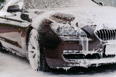 Oto yıkamada şampuanla yıkanmış köpükle kaplı bir araba resmi. Temizlik hizmeti konsepti. Köpüklü otomobil. Araç yıkama