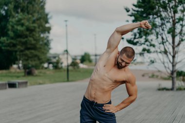 Etkin kaslı adamın açık havada çekimleri, esneme hareketleri, çıplak gövde pozları, açık havada antrenmanlar, büyük motivasyon, formda kalma. Kararlı sporcu daha güçlü bir vücuda doğru ilerliyor.