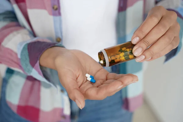 Female pour pills into palm, taking medicine, vitamins, painkiller or dietary supplement. Close up of woman\'s hands with medication capsules and medical jar. Health care, treatment, cure concept.