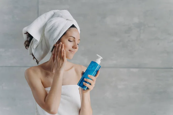 Banyo Havlularına Sarılmış Elinde Nemlendirici Duş Jeli Şampuan Tutan Güzel — Stok fotoğraf