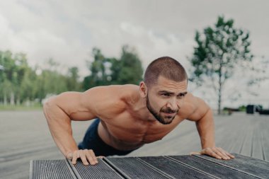 Aktif sakallı Avrupalı bir adamın yatay çekimi olması gerekenler, göğüs ve pazılar için egzersiz yapıyor, fiziksel olarak iyi durumda, dışarıda poz veriyor, kolları kaslı. Spor, egzersiz ve yükseltme kavramı