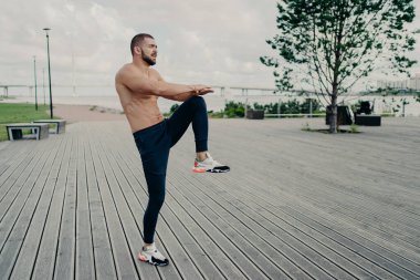 Sporcu adam sabahları spor yapıyor, bacaklarını kaldırıyor, aktif giysiler giyiyor, kardiyo eğitiminden önce ısınıyor. Açık havada başarılı sporcu egzersizleri yapıyor. Fiziksel olarak aktif bir adam egzersiz yapar.