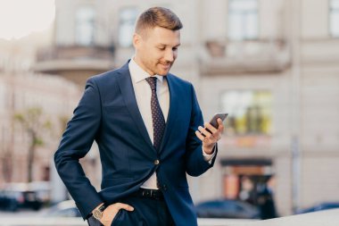 Başarılı erkek girişimcinin fotoğrafı modern akıllı telefonu elinde tutuyor, finans alışverişinden haberler okuyor, internette geziniyor, online ödemeler yapıyor, iş molası veriyor, kafeye ya da restorana gidiyor