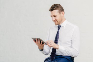 Pozitif başarılı erkek icra müdürü modern dokunmatik yüzey tutar, sosyal ağlar, yüksek hızlı internet bağlantısı, resmi gömlek kravat ile giyinmiş memnun net beslemeleri ilgili bildirim alır