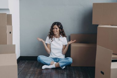 Nervous european woman has to pack the boxes. Girl is upset with moving. Annoyed young lady in jeans and white t-shirt is going to relocate. Homeowner getting stress from moving concept.