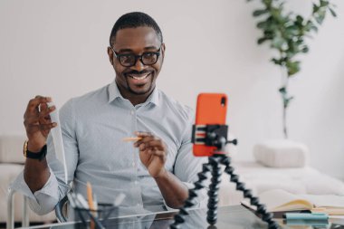 African american businessman presenting financial statistics by business corporate video call, using phone. Smiling friendly black male business coach teaching distantly online, showing document.