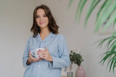 Bel keyifli çekim kadar Çizgili Pijamalı, uyanış sonra içecekler sıcak içecek giymiş genç kadın arıyorum sparre zaman evde var, karşı rahat iç kapalı duruyor. İnsanlar ve dinlenme kavramı