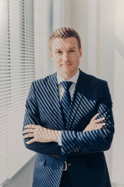 Ciddi erkek Yöneticisi tutar el dikey atış geçti, zarif siyah takım elbise giymiş, yakınındaki ofis pencere onun dolabında duruyor, iş günü, bir şey hakkında düşünüyor sonra sakin atmosferi sahiptir