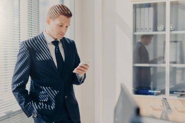 Çekici erkek yönetmen kurumsal kılığına girmiş, haber meslektaşları ile hisse, Internet'i kullanan, e-posta üstünde hareket eden telefon denetler, pencere ile kapamak yakınındaki rahat dolap, Bloglar Web sitesi duruyor