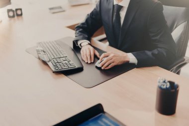 Başarılı erkek iş sahibinin kırpılmış görüntü resmi elbiseli iş yerinde oturur, iş bilgisayarı, mali rapor hazırlar. Erkek icra ofiste tek başına çalışıyor. İnsanlar ve mali