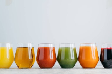 Bardakta oranganik içecek vartiety. Beyaz arka plan, yukarıda boş alan karşı satırda duran kavanozda çeşitli çok renkli suyu