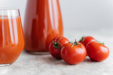 İki cam bardak domates suyu ve beyaz arka plan üzerinde küçük olgun kırmızı domates. Vitamin içeren taze içecek. Sağlıklı gıda