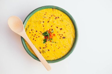 Yeşillik ve sebze ile sıcak kremsi lezzetli çorba, kase üzerinde tahta kaşık, beyaz arka plan üzerinde izole. Hindistan cevizli köri çorbası. Taze disn. Sağlıklı beslenme konsepti