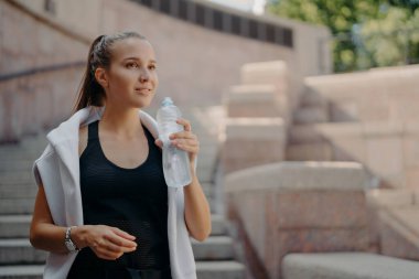 At kuyruklu atlet kadın, kardiyo eğitiminden sonra susar. İçecekler şişeden alınır. İçecekler susuz kalmaz.