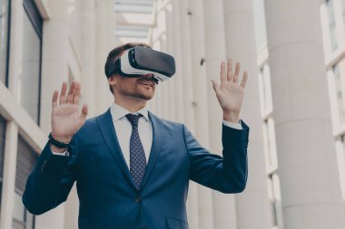 İşiniz için geleceğin teknolojileri. Sanal gerçeklik oyunu veya işi için VR kulaklığı kullanan Avrupalı işadamı, artırılmış gerçeklikte çalışırken 3D gözlük takıyor ve el kol hareketi yapıyor