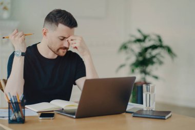 Stresli, düşünceli, serbest çalışan bir erkek ya da iş adamı kendini yorgun hissediyor ve iş yerinde bilgisayarla çalışırken sorunlar yaşıyor.