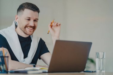 Mutlu sakallı adam, kağıt işleri hazırlıyor. Webinar ev saatlerinden uzaktan çalışıyor. İnternette yüksek hızlı internet bağlantısı kuruyor ve ortağıyla kulaklık görüşmeleri yapıyor. Çalışma zamanı.