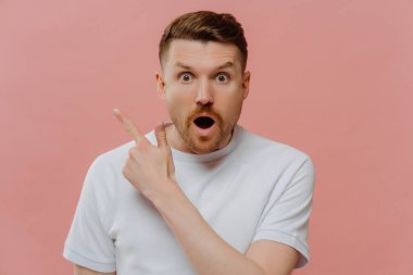 Şaşırdım, beyaz gömlekli genç adam parmak ucuyla fotokopi odasını işaret ediyor, hayret verici yüz ifadesi ile, pembe arka planda tek başına dururken fantastik bir şeyin reklamını yapıyor.