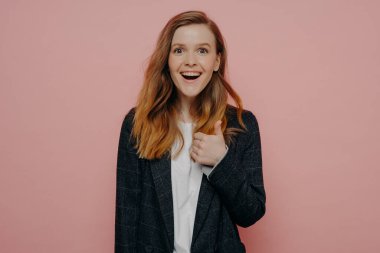 - Süper. Heyecanlı genç kızıl saçlı kadın portresi gündelik giysiler giyiyor baş parmağını gösteriyor, onaylama hareketi yapıyor. Kameraya hareketli bir şekilde bakıyor ve güveyi açık tutuyor. Stüdyo çekimi