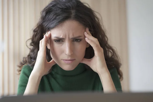 Concerned young italian woman employee looking at laptop computer screen with frustrated face expression, reading bad news by email, worried female office worker thinking of problem solution at work