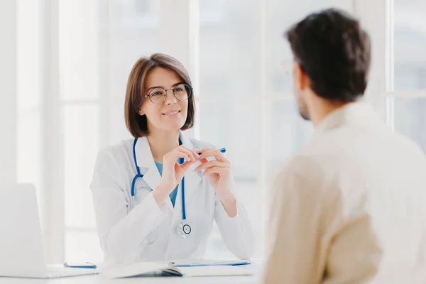 Kürklü profesyonel kadın doktor hastaların semptomlarını dikkatle dinler, sağlığını inceler, hasta kartına bilgi yazar, poz verir. Hasta erkek şikayet eder, kameraya döner.