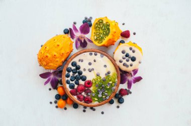 Kivano ve olgun meyveleri üst görünümü. Beyaz arka plan üzerinde izole lezzetli meyve ile Süt yüzlü. Etrafta mor orkideler var. Yatay atış