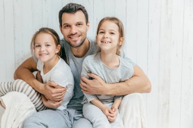 Mutlu genç baba portresi iki kızı kucaklayan, onları çok fazla poz birlikte evde seviyor. Güzel femle çocuklu bekar baba neşeli ifadeler var. Babalık kavramı