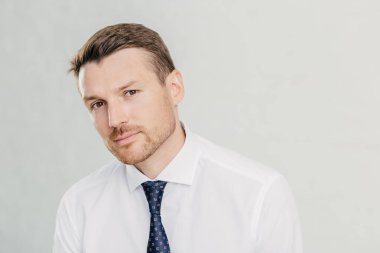 Kendine güvenen erkek ciddi kameraya benziyor, koyu renk gözleri ve anız, kravat, beyaz arka plan üzerinde izole ile zarif beyaz gömlek giymiş vardır. Dostum Yönetmen düşünüyor hakkında nasıl hayatta başarıya ulaşmak