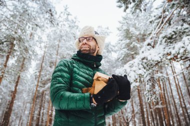 Görünüm aşağıdan yakacak odun tutar, yapacak görünüyor mutlu bir yana, ateş, güzel beyaz ağaçlar karşı duruyor, orman görkemli ortamda hayran, hafta sonları açık havada geçirir. İnsanlar, kış konsepti