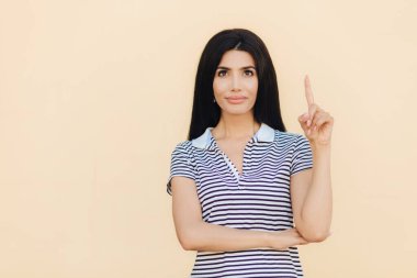 Yatay rüya gibi ifade ile çekici erkek portresi dolgun dudaklar ve yapmak vardır, rahat çizgili t gömlek giyer, ile gösterir ön yukarı doğru parmak, reklam için boş alanı gösterir