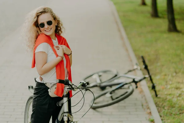 Alegre Encaracolado Feminino Pára Durante Caminho Poses Bicicleta Estrada Amigos — Fotografia de Stock
