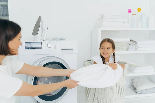 Una niña pone ropa sucia en la canasta. limpieza y lavandería del hogar.