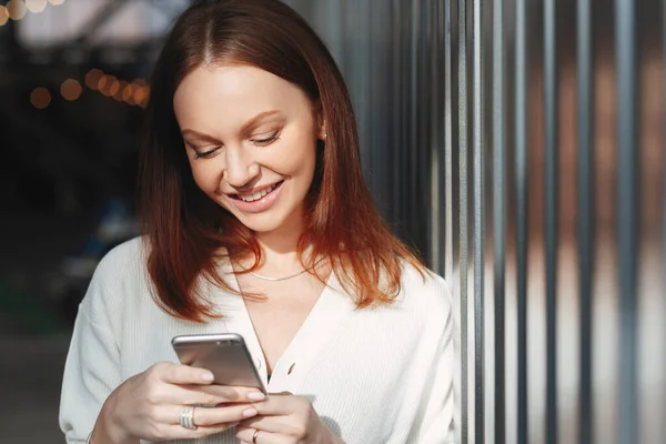 Радостная Женщина Сосредоточена Экране Мобильного Телефона Проверяет Почтовый Ящик Одетый — стоковое фото