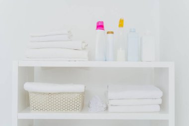 Temiz katlanmış havluları, bir şişe sıvı yıkaması ya da deterjanı olan çamaşır odası. Her şey beyaz renkli. Günlük ev işleri ve çamaşır günü.