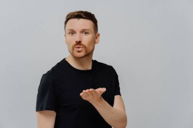 Tipik siyah tişörtlü, genç, yakışıklı, tıraşsız bir adam sevgilisine hava öpücüğü yolluyor. Gri stüdyo arka planında tek başına dikilirken aşkını ifade etmeye ya da flört etmeye çalışıyor.