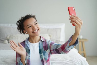Videolu telefon görüşmesi. Kıvırcık Afrikalı Amerikalı kadın cep telefonuyla arkadaşıyla konuşuyor. Genç bayan kameranın önünde konuşuyor ve el sallıyor. Sanal iletişim konsepti. Genç kız yaşam tarzı..