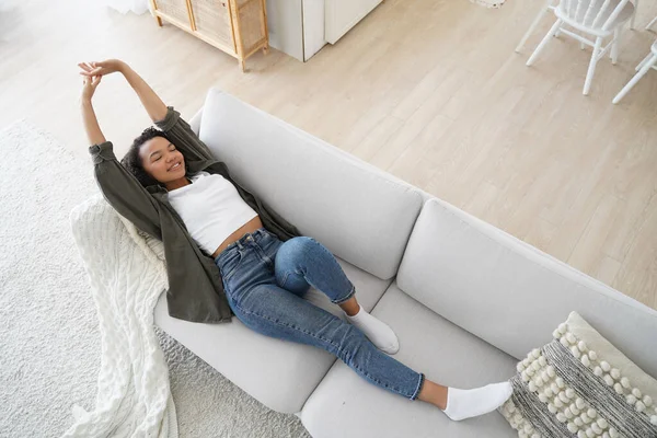 stock image Young woman lying on comfy sofa. Smiling girl stretching body awaking after sleep on cozy couch breath fresh air inside modern living room, enjoying leisure, break, weekend. Recreation, stress relief.