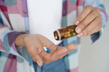 Close-up woman's hands holding pills and medicine jar. Female takes remedy, medication, painkillers, dietary supplement or vitamins. Modern pharmacy for body and mental health.