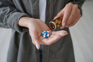 Drug addiction. Hand of african american girl holding medicine drugs and flacon. Teenage spanish girl or young woman taking vitamins or painkillers. Medications and pharmaceutical treatment.