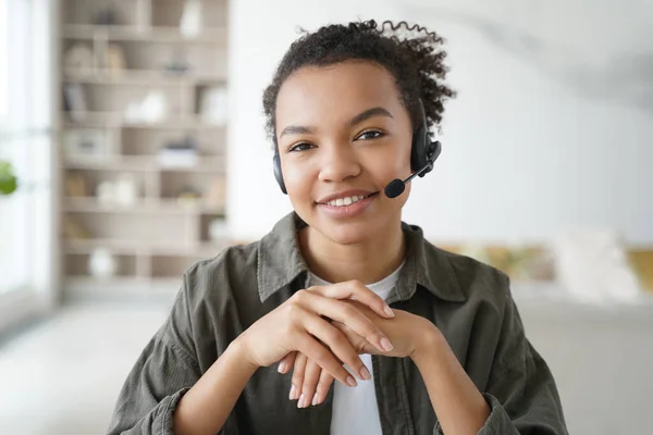 虚拟助手 戴耳机的年轻妇女提供咨询 隔离方面的远程研究 戴耳机的非洲经理面带微笑 客户支持服务操作员从家里进行的远程工作 — 图库照片